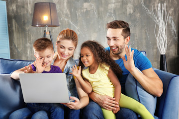 Happy interracial family with laptop on sofa