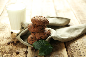 Fototapeta na wymiar Delicious coffee cookies on napkin and glass of milk on wooden table