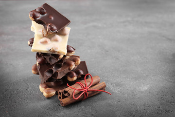 Chocolate pieces with nuts and cinnamon sticks on grey background