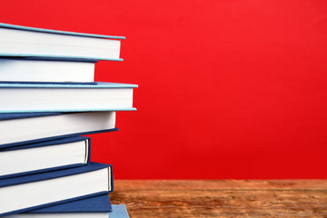 Pile of books on wooden table and red background