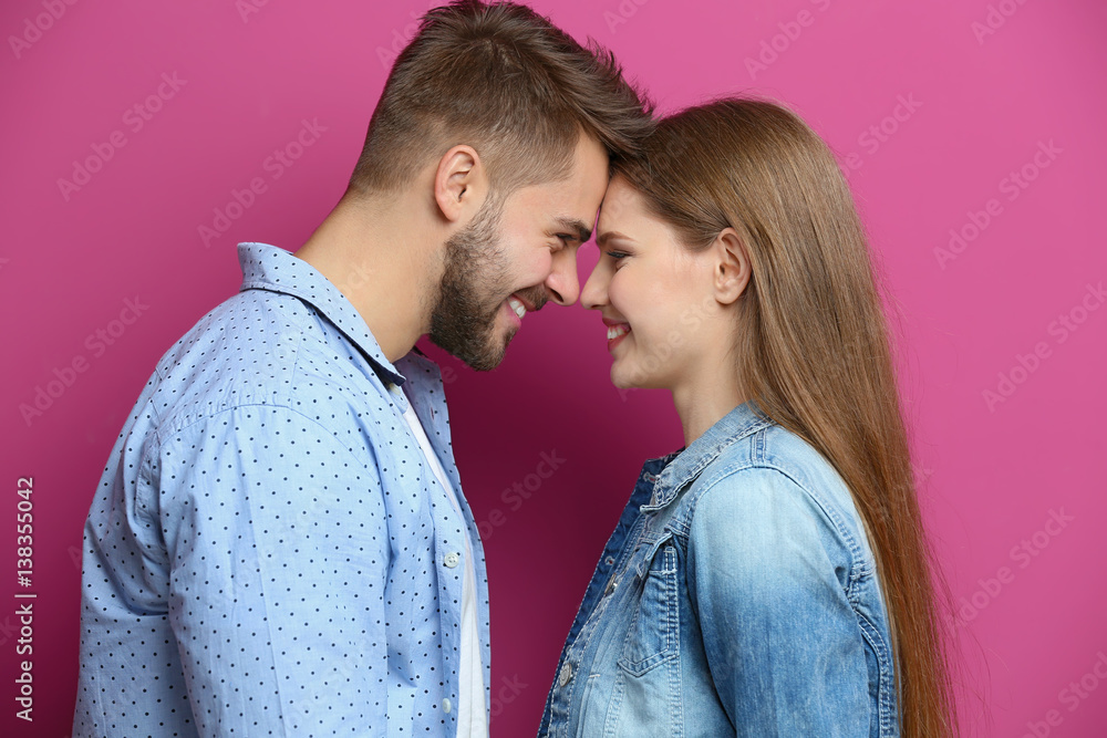 Wall mural Cute young couple on color background