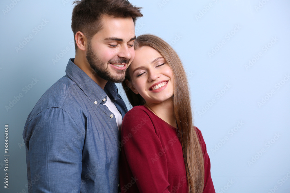 Wall mural Cute young couple on color background