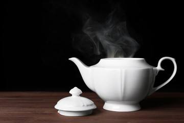 Teapot with hot water on dark background