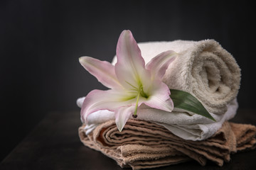 Obraz na płótnie Canvas Beautiful spa composition with towels and lily flower on dark background