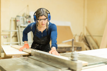 Female carpenter using a table saw