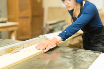 Female carpenter cutting wood with a saw