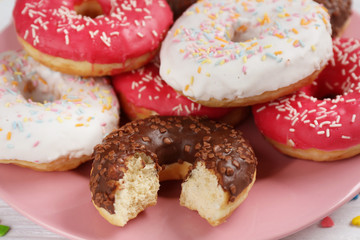 Tasty glazed donuts on plate, closeup