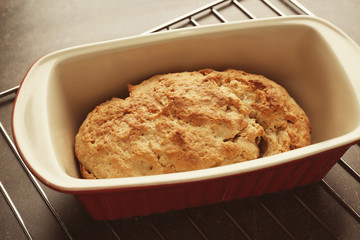 Tasty loaf of beer bread in baking dish on table