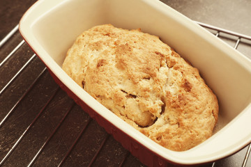 Tasty loaf of beer bread in baking dish on table