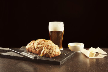 Board with tasty loaf of beer bread on table