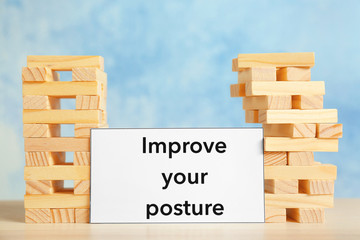 White paper with phrase IMPROVE YOUR POSTURE and wooden blocks on table
