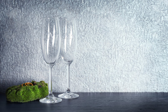 Moss with wedding rings and champagne glasses on table and grey wall background