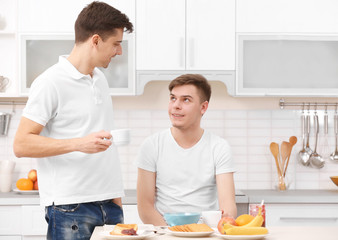 Happy gay couple having breakfast in kitchen