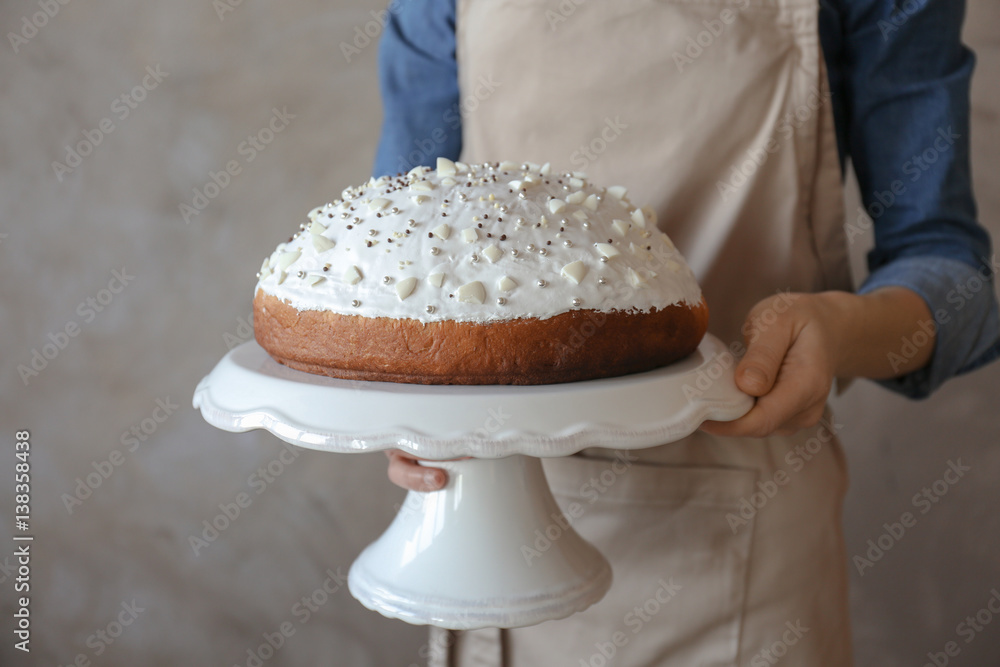 Wall mural Man holding Easter cake on light background