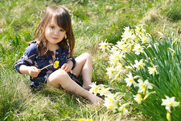 Little country girl with flowers in sunny spring day