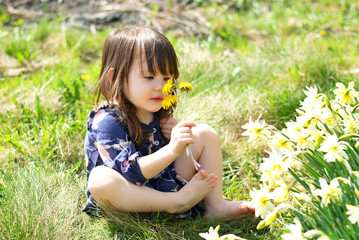 Little country girl with flowers in sunny spring day