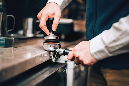 Barista using coffee machine preparing fresh coffee with latte foam at coffee shop and restaurant, bar or pub.