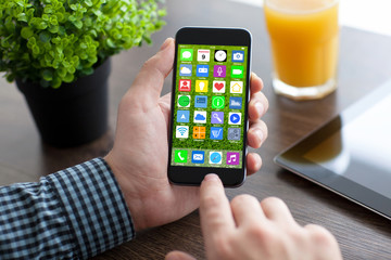 man hands holding phone with home screen icons apps