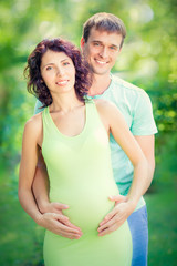 Happy man hugging belly of pregnant woman