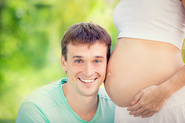 Happy man holding belly of pregnant woman