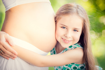 Obraz premium Happy child holding belly of pregnant woman