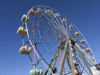 Looking up  into ferris wheel gondolas with blue sky.