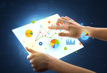 Hands touching a glass-like tablet with charts