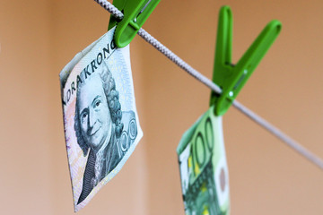 Green banknotes 100 euro and 100 swedish crownes in a green clothes peg
