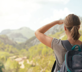 Woman with backpack enjoying view in mountains.