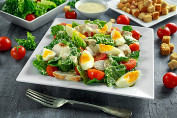 Fresh healthy Caesar salad with chicken, eggs, tomatoes, Cheese and Croutons on white plate