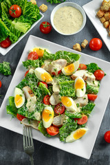 Fresh healthy Caesar salad with chicken, eggs, tomatoes, Cheese and Croutons on white plate
