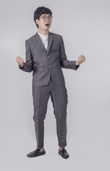 Young handsome business man in gray suit and glasses feel success with gray background