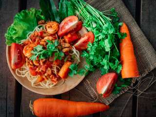  spaghetti chicken and shrimp on tomato sauce on wooden background