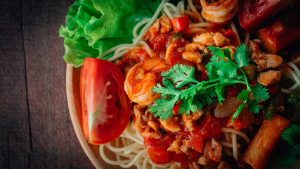  spaghetti chicken and shrimp on tomato sauce on wooden background