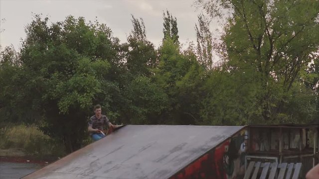 The slow movement of the guy that makes overclocking on the asphalt on a bicycle BMX, then jumps in the air due to the ramp and makes a stunts, spinning bike, holding it just behind the wheel.