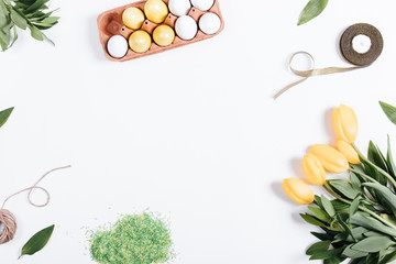 Easter composition on the white background: tulips, painted eggs, ribbon