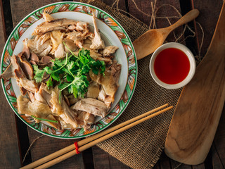 Vintage style Thai traditional food chicken boiled with sauce and spicy chili sauce on top with wooden background wallpaper