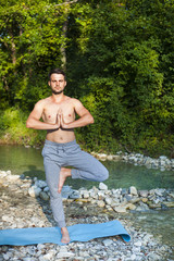 Man meditating near the mountain river. Yoga practicing outdoors.
