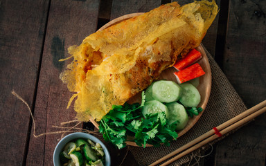 Vintage style Thai traditional food stuffed crispy egg crepe on top and wooden background wallpaper