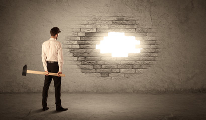 Business man hitting brick wall with hammer and opening a hole