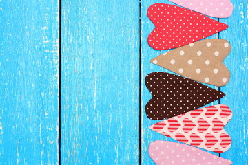 Obraz premium Colorful handmade hearts from fabric on background of blue boards. Love and romance. Feelings