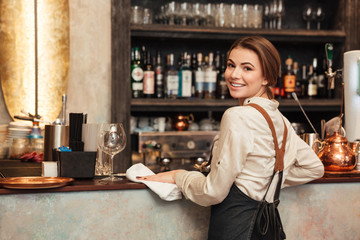 Young woman bartender standing in cafe.