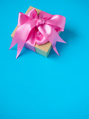 one gift box with pink satin ribbon on a blue background, space for text