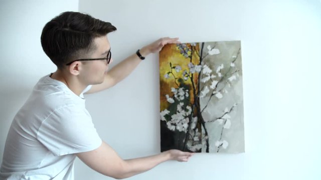 young couple choosing point for picture on wall at home