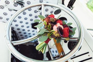 wedding bouquet made of red and biege peony on a chrome wheel of retro car