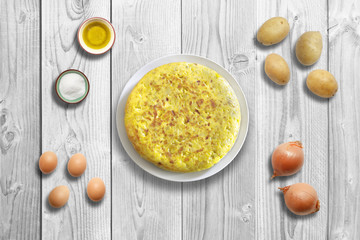 Traditional spanish omelette on marble wooden background with ingredients.