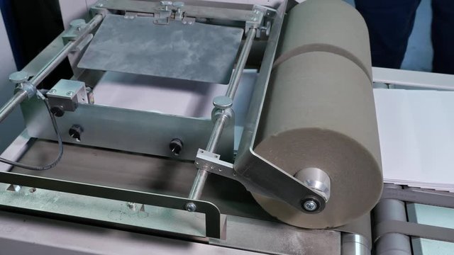 Passing white envelopes by machine in a factory, close up