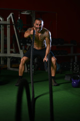 Fototapeta na wymiar Young Man Battling Ropes At Gym Workout Exercise