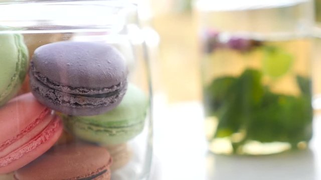 Cup of mint tea with macaroons and marshmallows. Beautiful sunny day in spring. Green and yellow background. French bakery with hot tea. Tasty breakfast, spring mood.