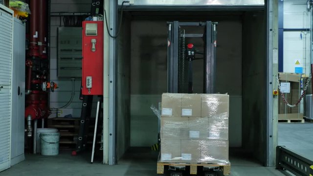 Forked Automatic Guided Vehicles (AGV) pallet truck goes into an elevator